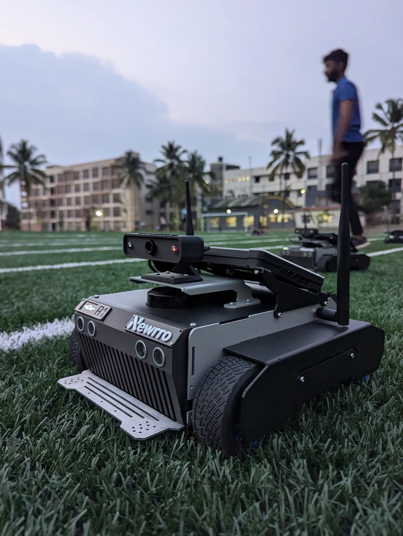 ARJUNA on a turf field at dusk, with a team member in the background