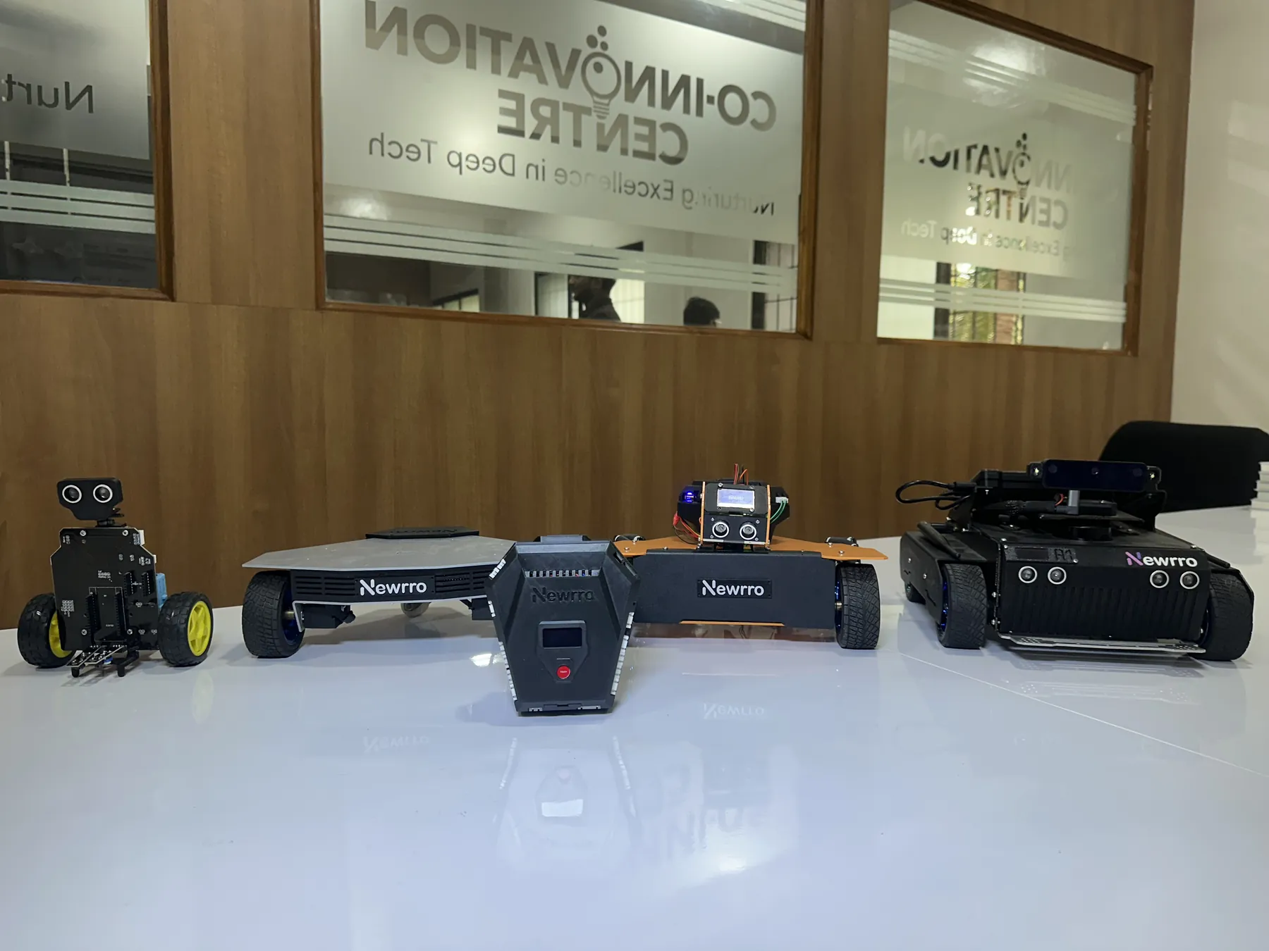 A line-up of Newrro robots and a controller on a white table at a Co-Innovation Centre